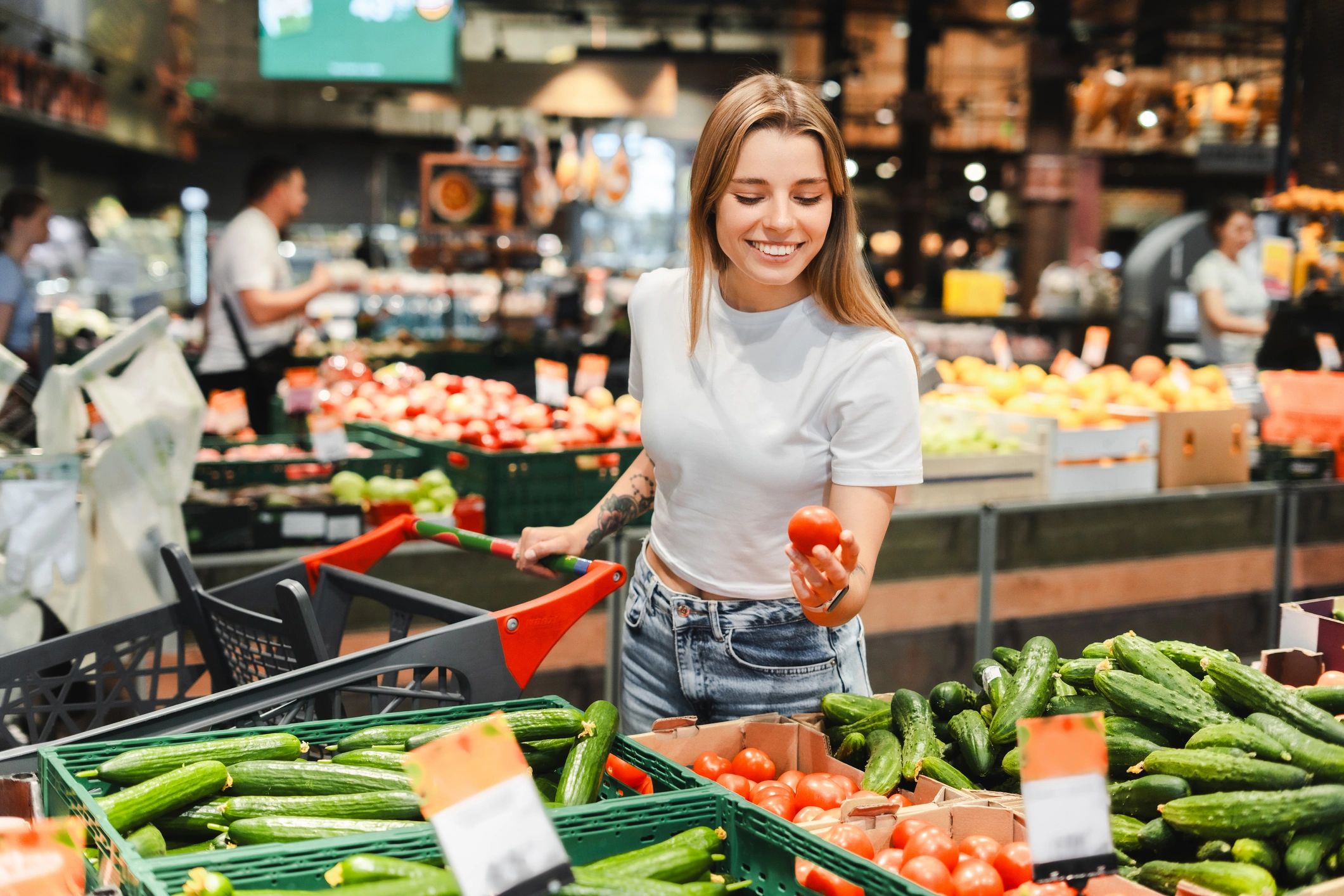 Person choosing fresh tomatoes in a grocery store produce aisle