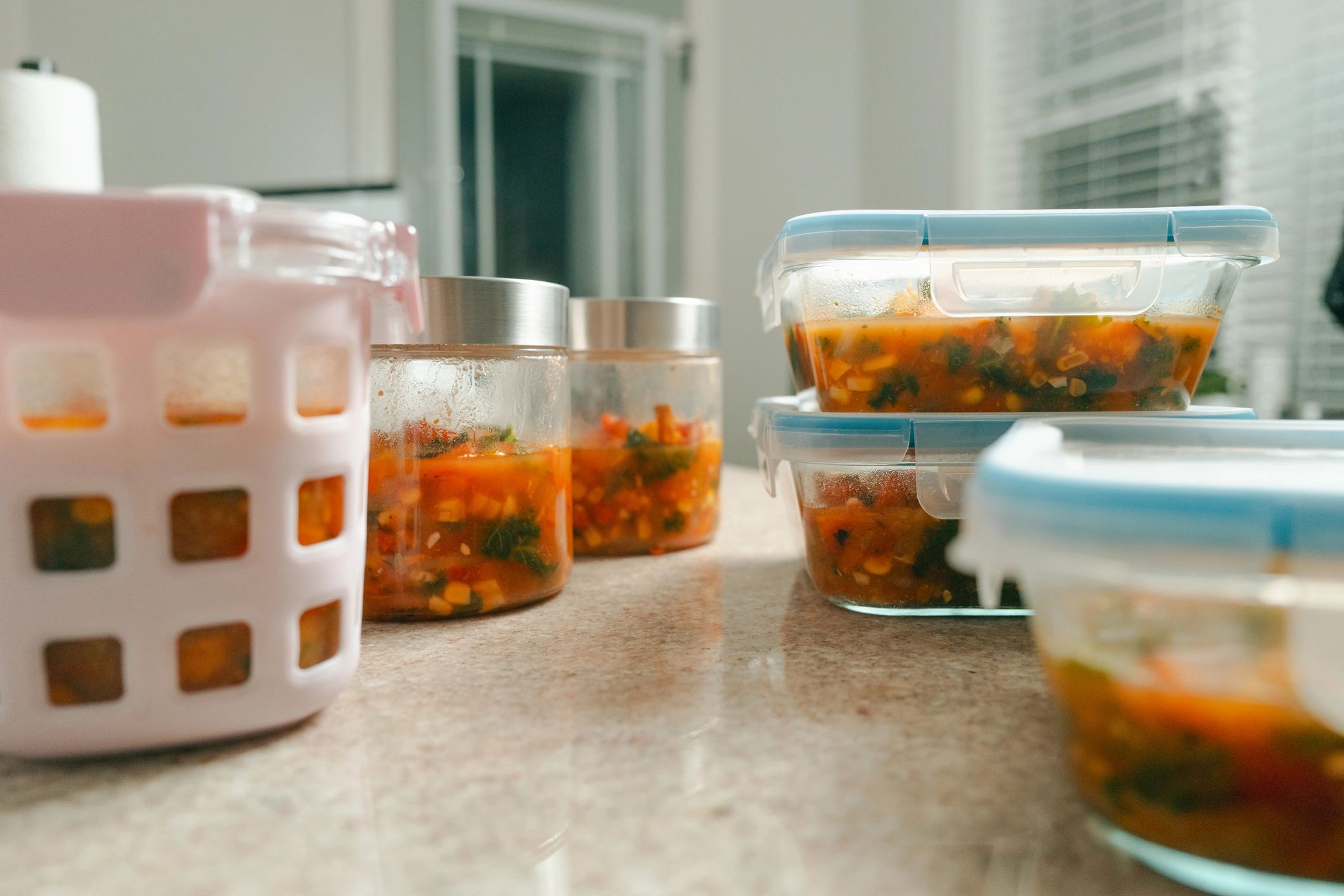 Meal prep containers filled with healthy soup and vegetables