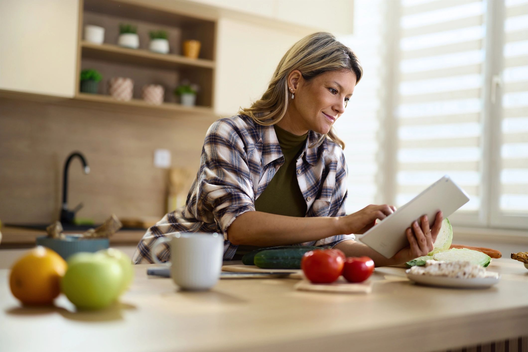 Person using a tablet in the kitchen while preparing food