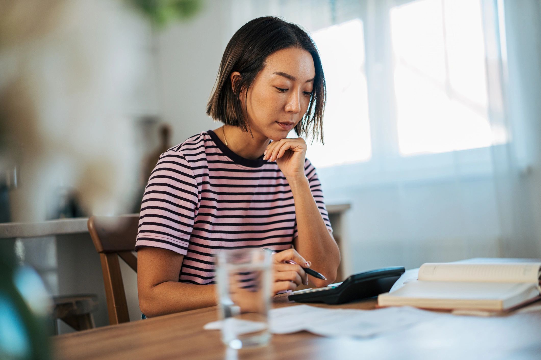 Person using a calculator and notebook to plan a monthly budget